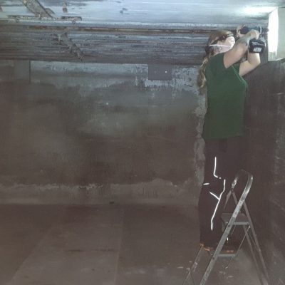 Rangerin bringt Fledermausstein im Bunker an